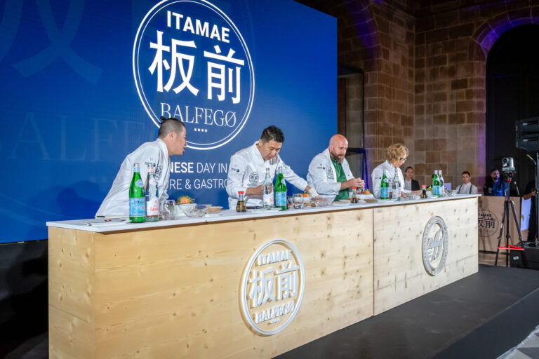 Cuatro sushichefs trabajando tras la barra de madera de ITAMAE Balfegó, con el logotipo grabado, ante el jurado.